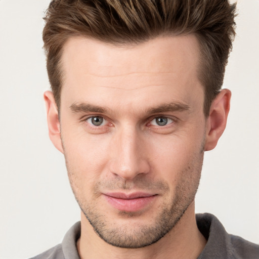 Joyful white young-adult male with short  brown hair and grey eyes