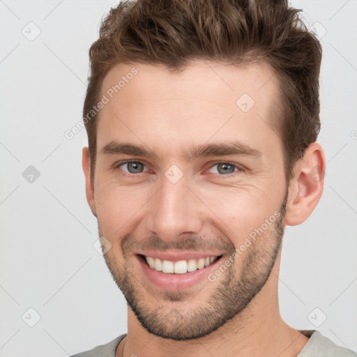 Joyful white young-adult male with short  brown hair and grey eyes