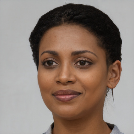 Joyful black young-adult female with short  black hair and brown eyes