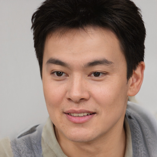 Joyful asian young-adult male with short  brown hair and brown eyes