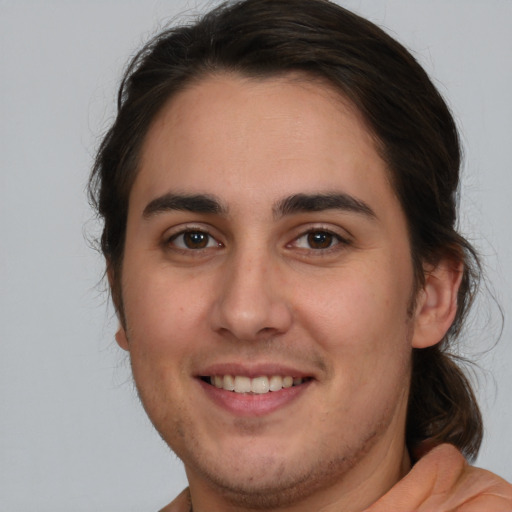 Joyful white young-adult male with long  brown hair and brown eyes