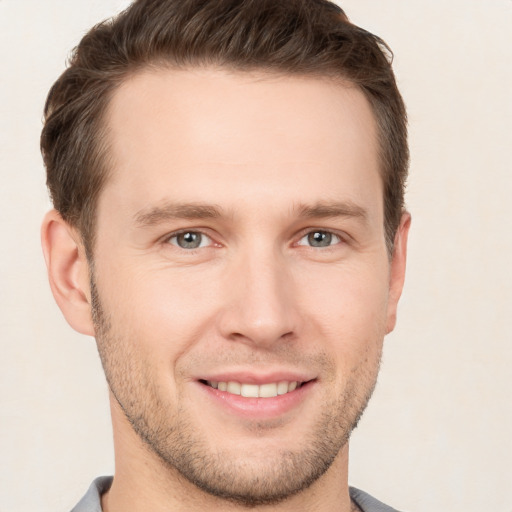 Joyful white young-adult male with short  brown hair and grey eyes