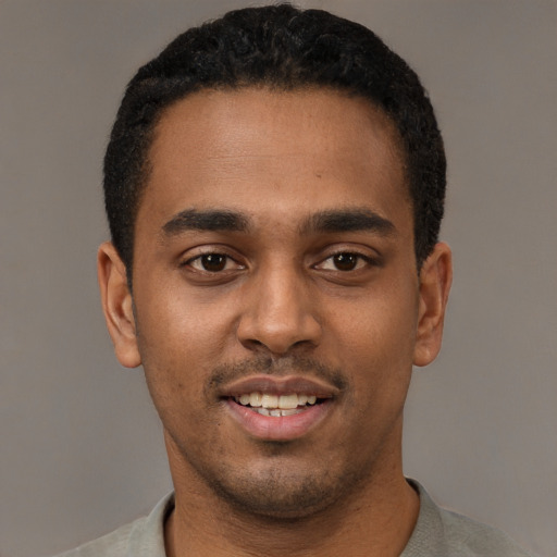 Joyful black young-adult male with short  black hair and brown eyes