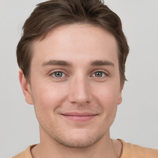 Joyful white young-adult male with short  brown hair and grey eyes