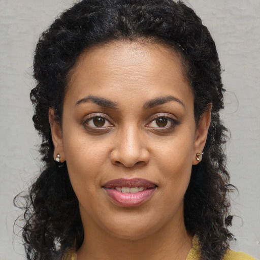 Joyful black young-adult female with long  brown hair and brown eyes