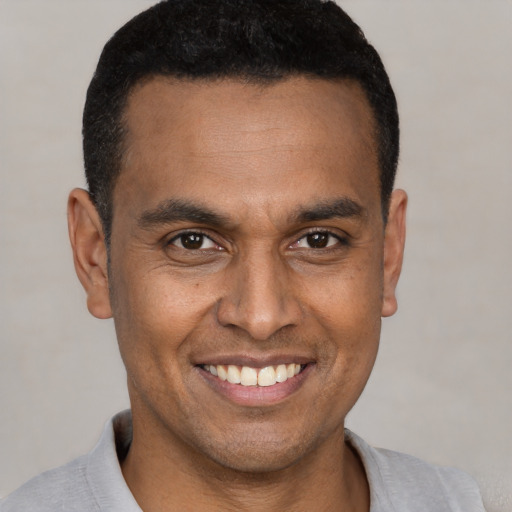 Joyful black young-adult male with short  black hair and brown eyes