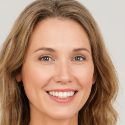 Joyful white young-adult female with long  brown hair and green eyes