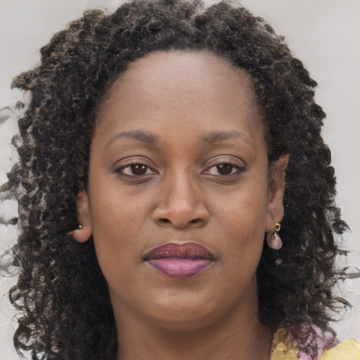 Joyful black adult female with long  brown hair and brown eyes