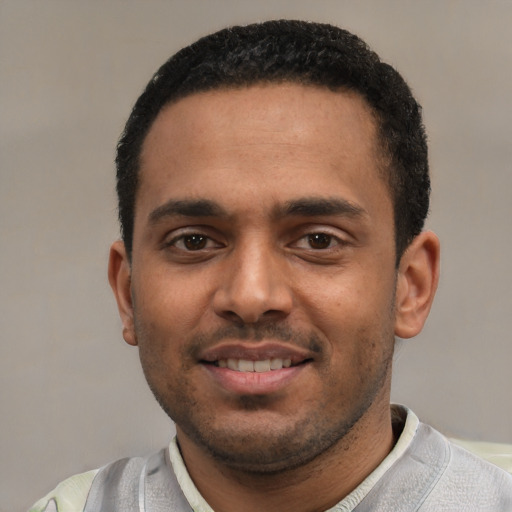 Joyful black young-adult male with short  black hair and brown eyes