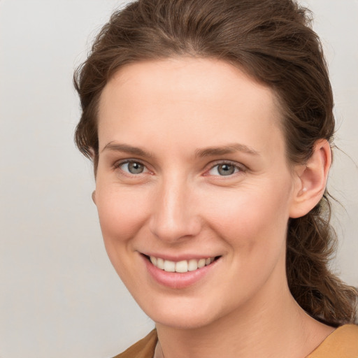 Joyful white young-adult female with medium  brown hair and grey eyes