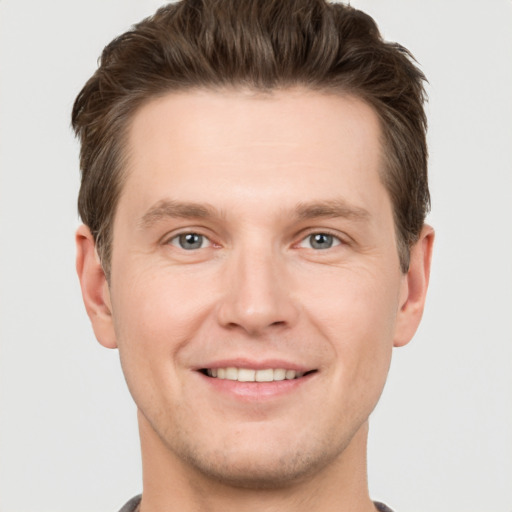 Joyful white young-adult male with short  brown hair and grey eyes