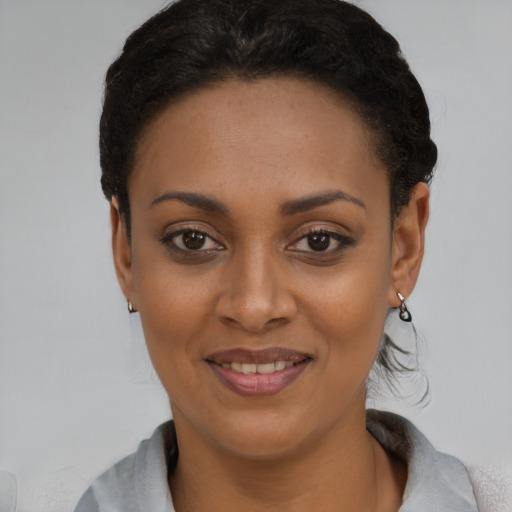 Joyful black young-adult female with short  black hair and brown eyes