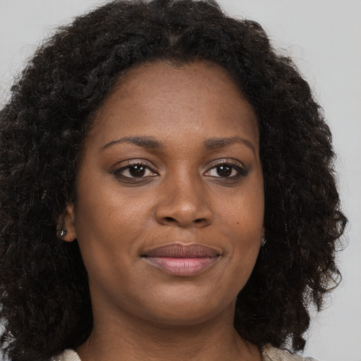 Joyful black young-adult female with long  brown hair and brown eyes