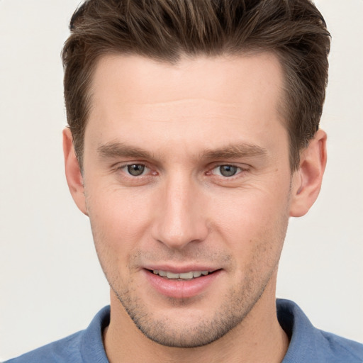 Joyful white young-adult male with short  brown hair and grey eyes