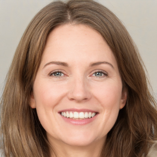 Joyful white adult female with long  brown hair and green eyes