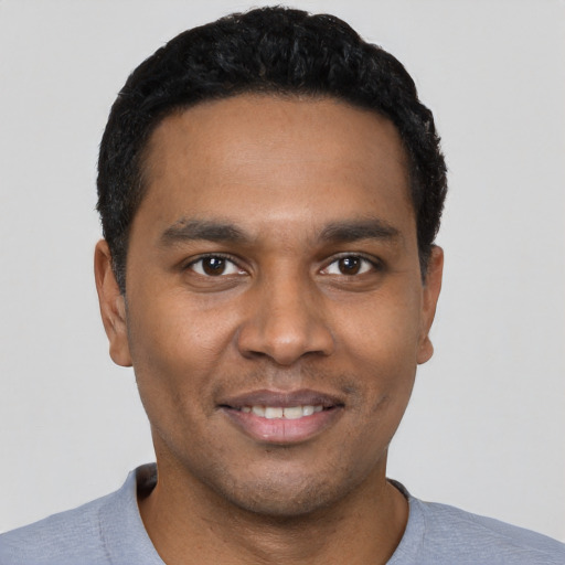 Joyful black young-adult male with short  black hair and brown eyes