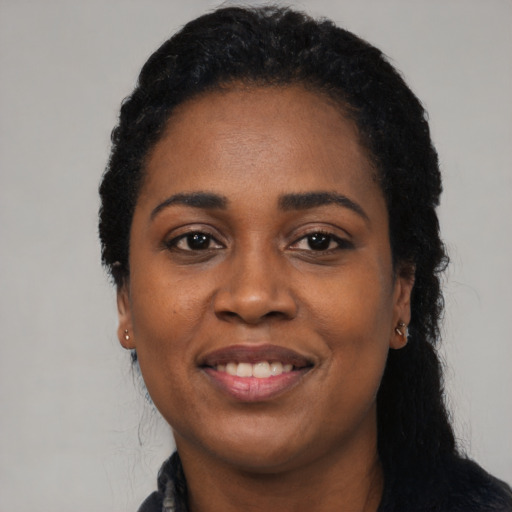 Joyful black young-adult female with long  black hair and brown eyes