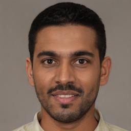 Joyful latino young-adult male with short  black hair and brown eyes