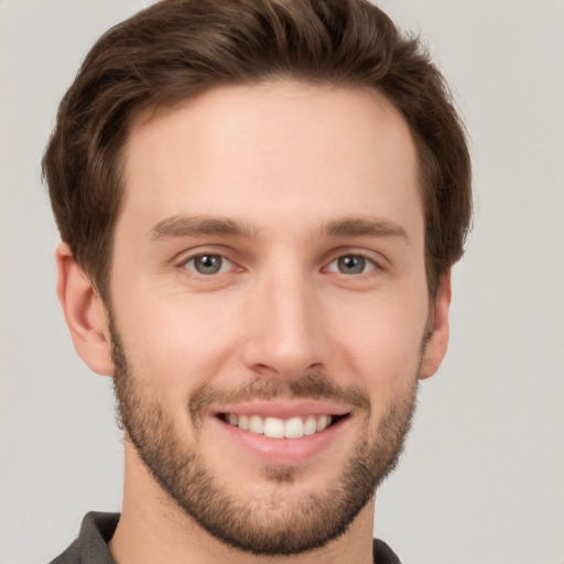 Joyful white young-adult male with short  brown hair and grey eyes