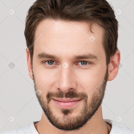 Joyful white young-adult male with short  brown hair and grey eyes