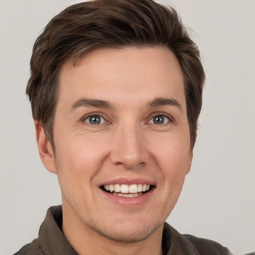 Joyful white young-adult male with short  brown hair and grey eyes