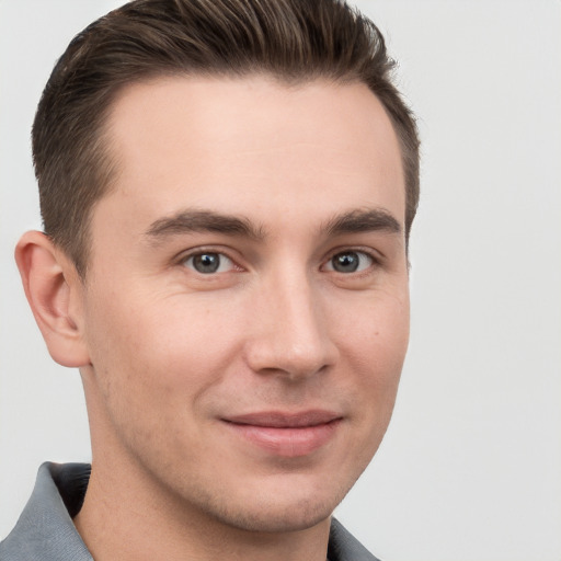 Joyful white young-adult male with short  brown hair and grey eyes