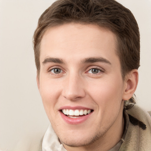 Joyful white young-adult male with short  brown hair and grey eyes