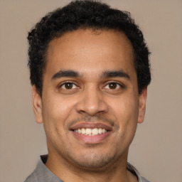 Joyful latino young-adult male with short  brown hair and brown eyes