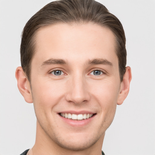 Joyful white young-adult male with short  brown hair and grey eyes