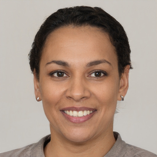 Joyful latino young-adult female with short  black hair and brown eyes