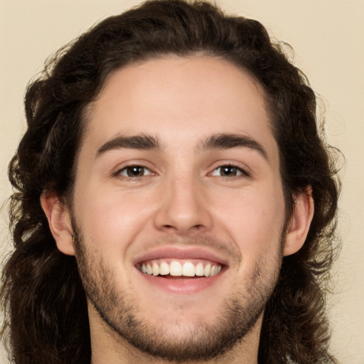 Joyful white young-adult male with long  brown hair and brown eyes