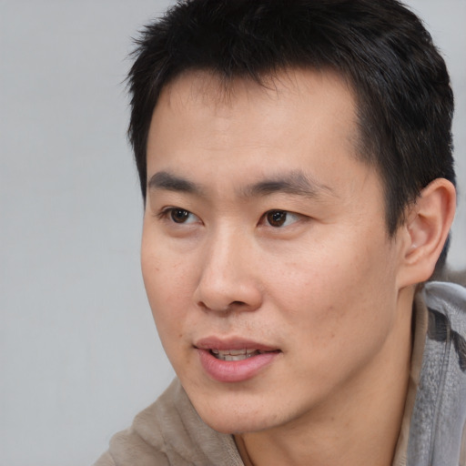 Joyful asian young-adult male with short  black hair and brown eyes