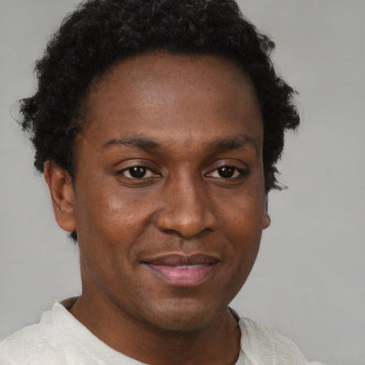 Joyful black young-adult male with short  brown hair and brown eyes