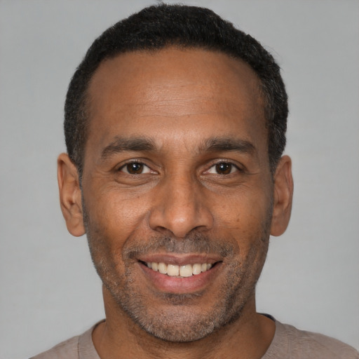 Joyful black adult male with short  black hair and brown eyes