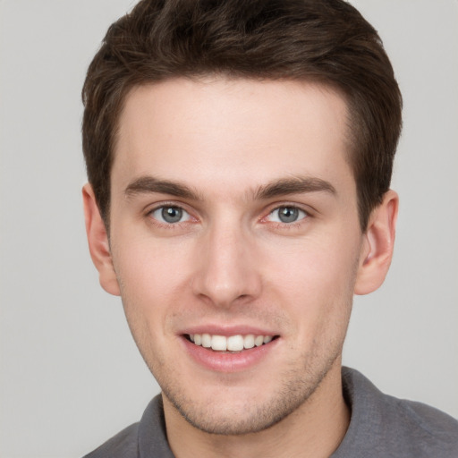 Joyful white young-adult male with short  brown hair and grey eyes