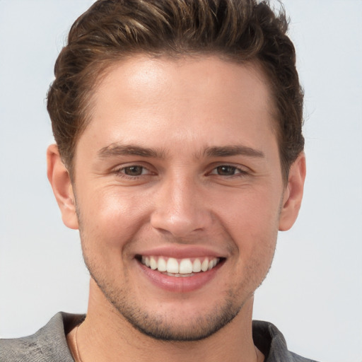 Joyful white young-adult male with short  brown hair and grey eyes