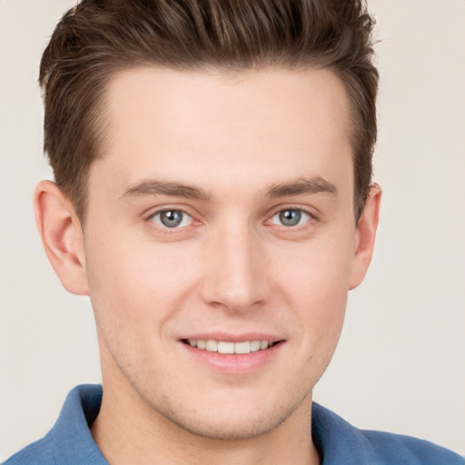 Joyful white young-adult male with short  brown hair and grey eyes