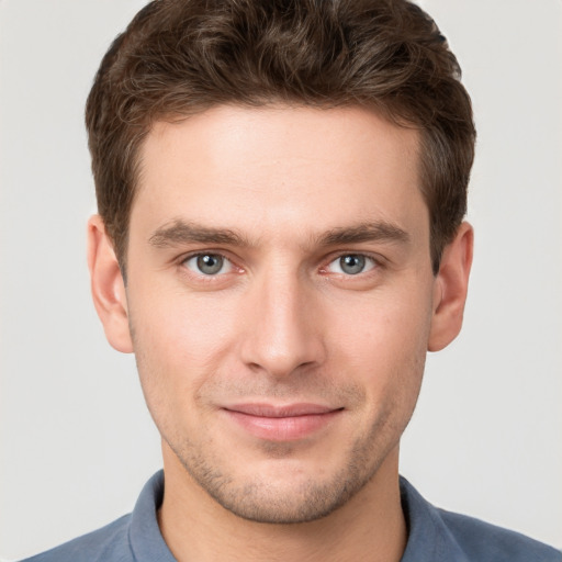 Joyful white young-adult male with short  brown hair and grey eyes