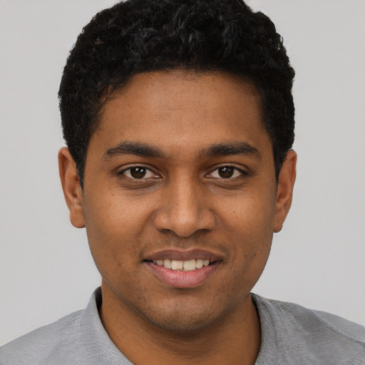 Joyful black young-adult male with short  black hair and brown eyes