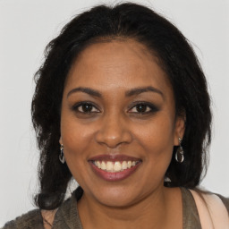 Joyful black young-adult female with long  brown hair and brown eyes