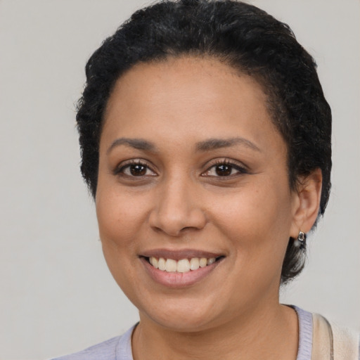 Joyful black young-adult female with short  black hair and brown eyes
