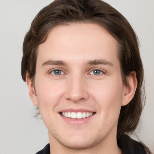 Joyful white young-adult male with medium  brown hair and grey eyes