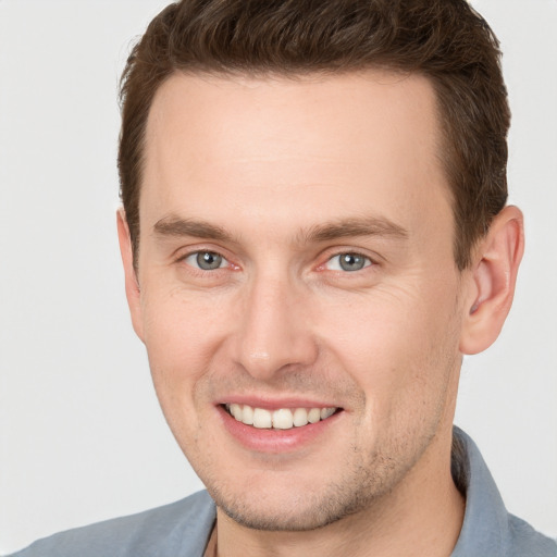 Joyful white young-adult male with short  brown hair and grey eyes