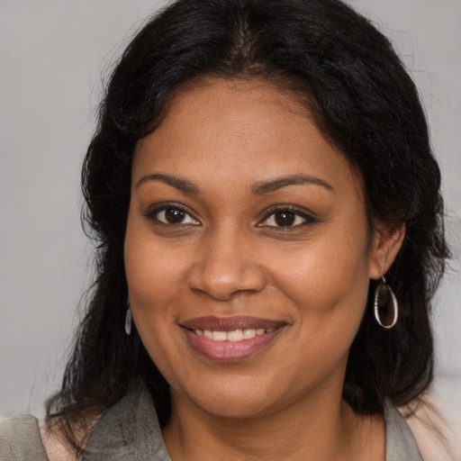 Joyful black young-adult female with long  brown hair and brown eyes