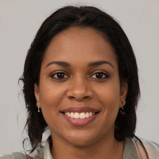 Joyful black young-adult female with long  brown hair and brown eyes