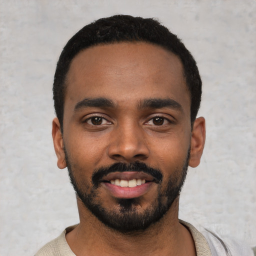 Joyful black young-adult male with short  black hair and brown eyes