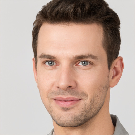 Joyful white young-adult male with short  brown hair and grey eyes