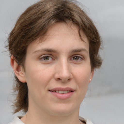 Joyful white young-adult female with medium  brown hair and grey eyes