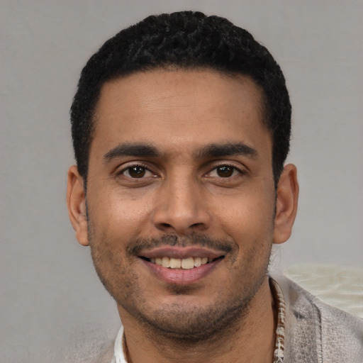 Joyful latino young-adult male with short  black hair and brown eyes