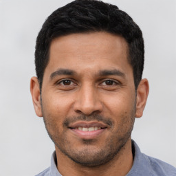 Joyful latino young-adult male with short  black hair and brown eyes